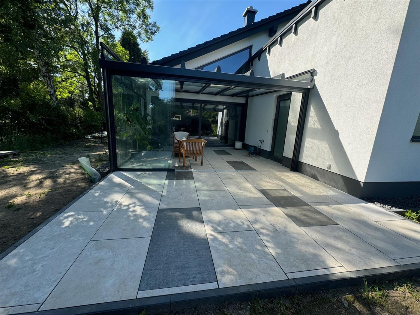 Terrasse aus Travertin und norwegischem Schiefer an einem Wohnhaus mit Wintergarten in Falkensee